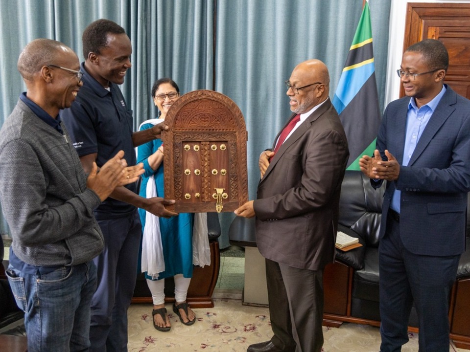 From Left Philip Moatlhodi and Dennis Mukasa are gifted a mini Zanzibar door by Hon. Nassor Ahmed Mazrui (Minister of Health, Zanzibar) as Dr .Mngereza Mzee Miraji (Secretary General, Ministry of Health, Zanzibar) and (Center) Laxmi Bhawani Majji (Chief, UNICEF Zanzibar Office) look on in the Ministry of Health offices, Zanzibar on August 27th, 2025